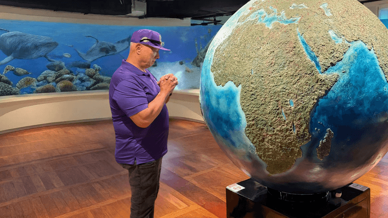 "Apostle Constantine I. Nightingdale, in front of a globe artwork, exemplifying leadership and spiritual growth in his ministry."