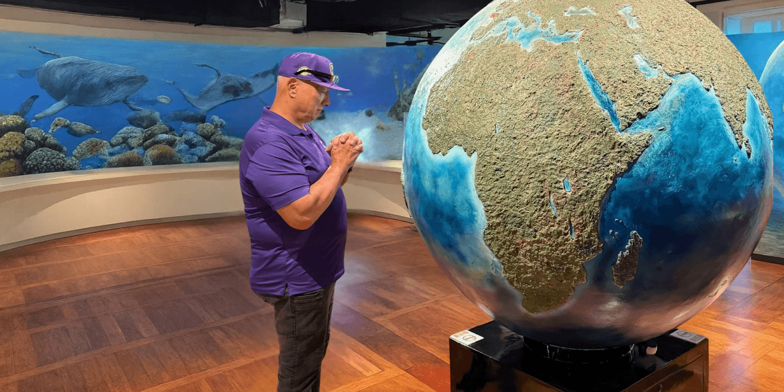 "Apostle Constantine I. Nightingdale, in front of a globe artwork, exemplifying leadership and spiritual growth in his ministry."