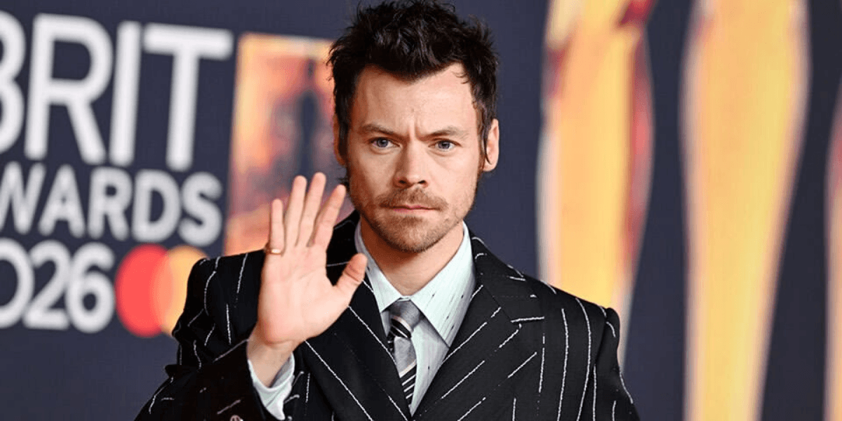 Man in pinstriped suit waving at the camera on a red carpet event