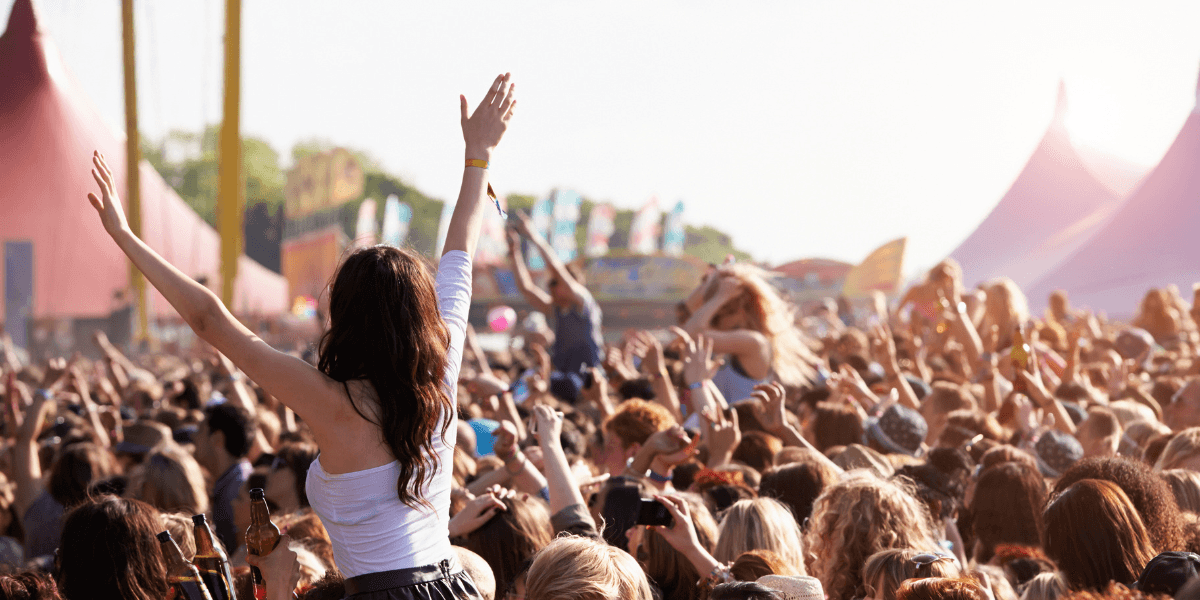 Crowd at a music festival with a woman on someone's shoulders celebrating joyfully