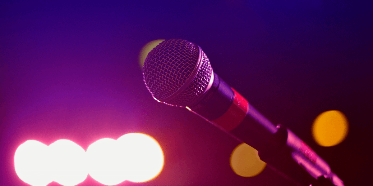 Close-up of a microphone against a colorful, blurred background of stage lights