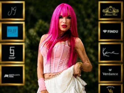 A woman with vibrant pink hair poses confidently for a photo, embodying the spirit of music and healing.