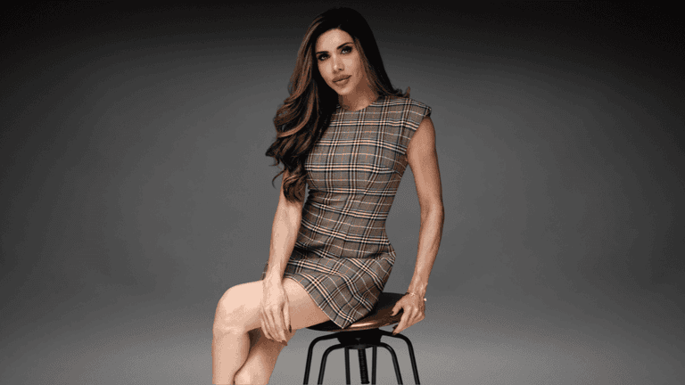 Lisa Haven seated on a stool wearing a plaid dress during a professional portrait for her founder profile.