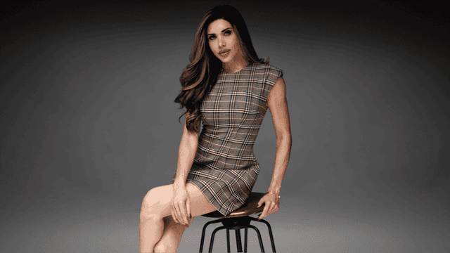 Lisa Haven seated on a stool wearing a plaid dress during a professional portrait for her founder profile.