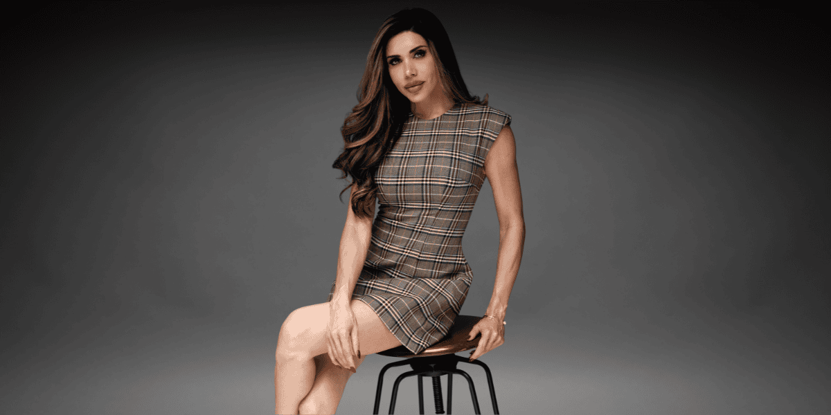 Lisa Haven seated on a stool wearing a plaid dress during a professional portrait for her founder profile.