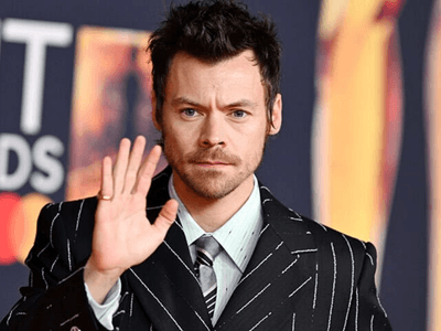 Man in pinstriped suit waving at the camera on a red carpet event