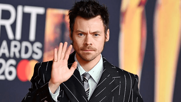Man in pinstriped suit waving at the camera on a red carpet event