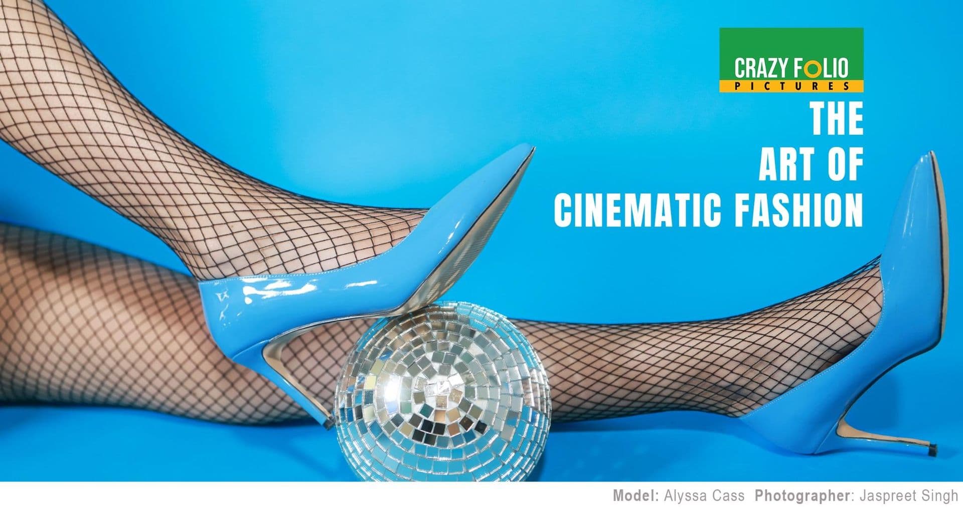 A pair of blue high heels on fishnet stockings next to a disco ball
