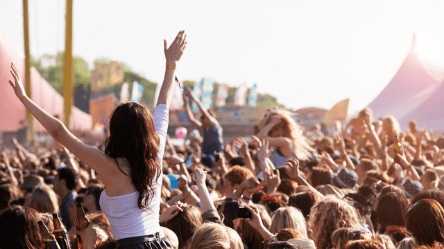 Crowd at a music festival with a woman on someone's shoulders celebrating joyfully