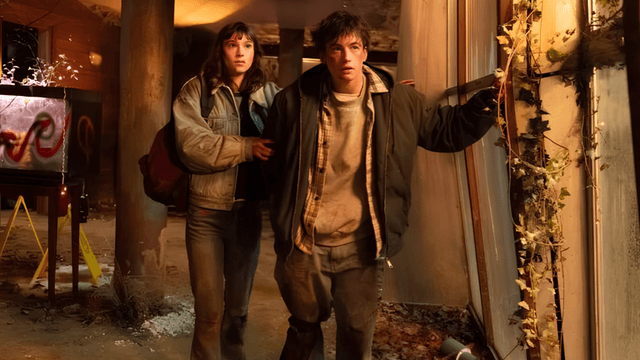 Two characters explore a dilapidated building, looking cautious amidst debris and dim lighting