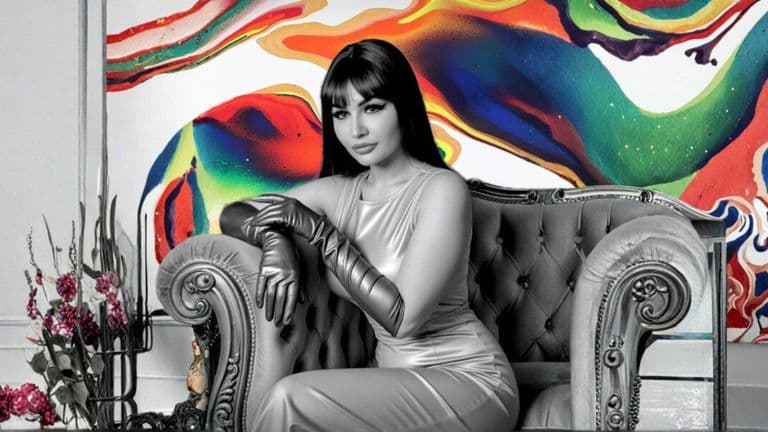 A model in a sleek silver outfit sits confidently on a vintage chair, with vibrant abstract artwork as the backdrop.