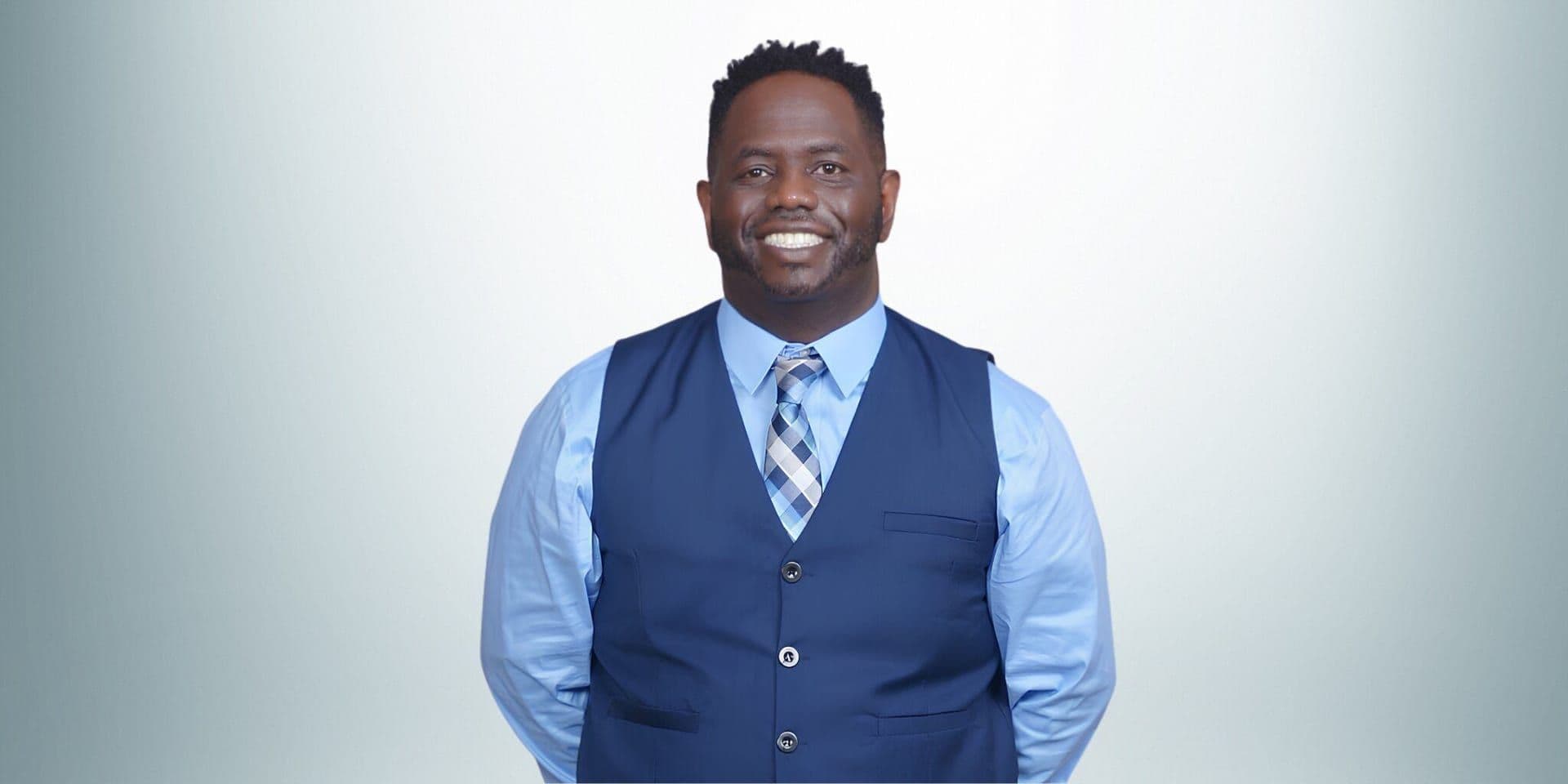 Rashad Woods, a black man in a blue shirt and vest, leads The T.R.O.N. Podcast, inspiring growth through global conversations.
